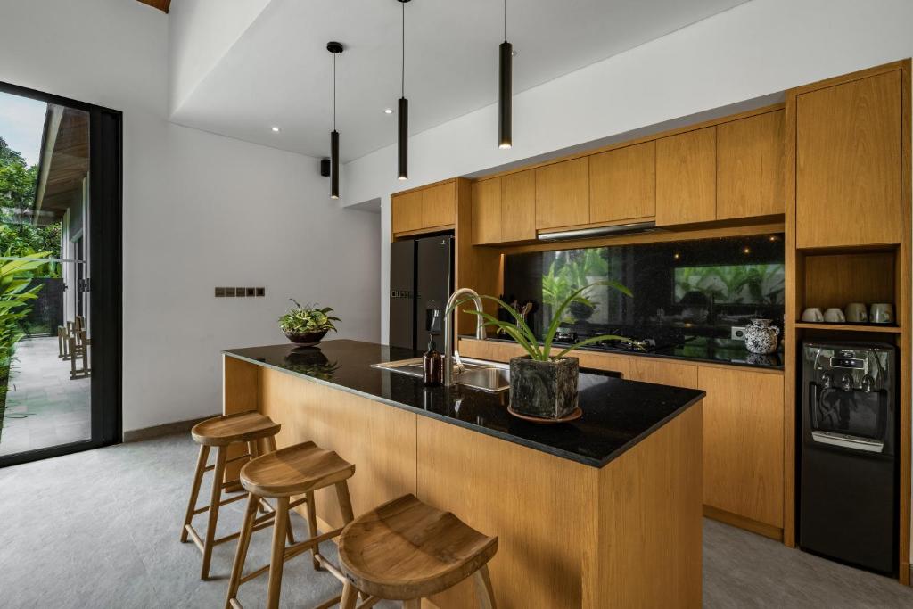 a kitchen with a sink and a counter with stools at Villa Welcome by BaliSuperHost in Ubud