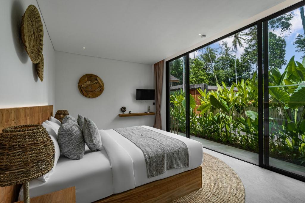 a bedroom with a bed and a large window at Villa Welcome by BaliSuperHost in Ubud
