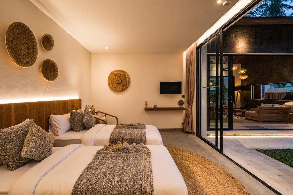 two beds in a hotel room with a patio at Villa Welcome by BaliSuperHost in Ubud