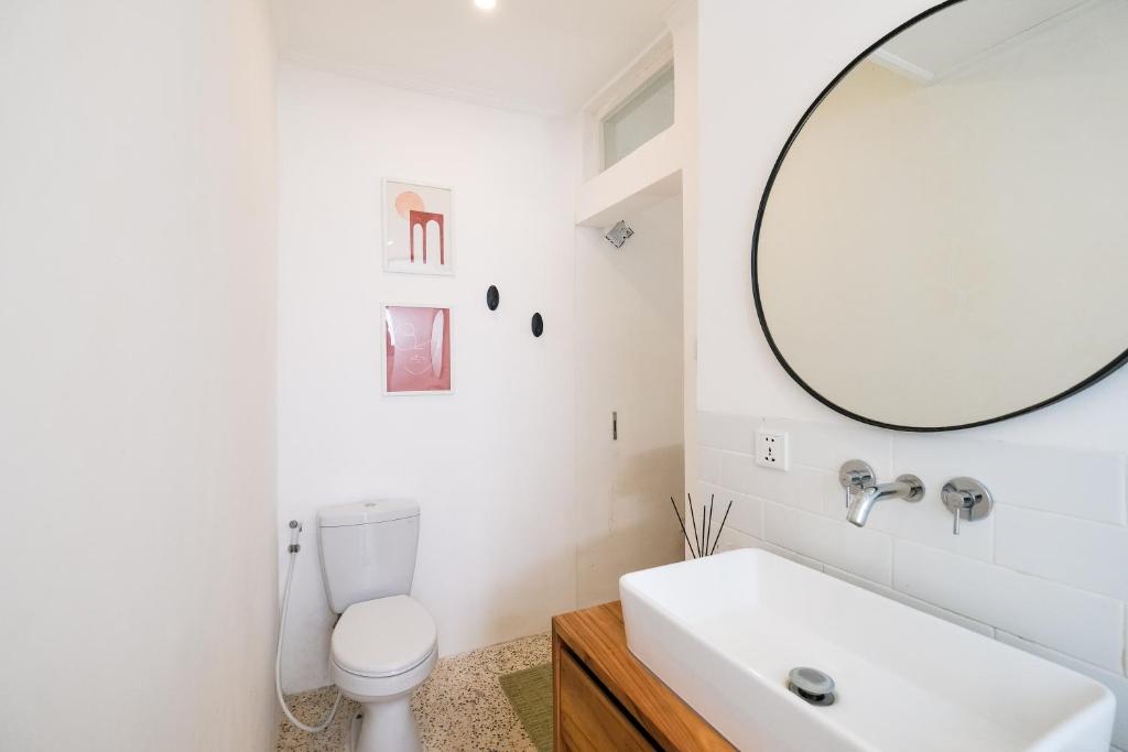 a white bathroom with a sink and a mirror at Villa Naia Berawa in Canggu