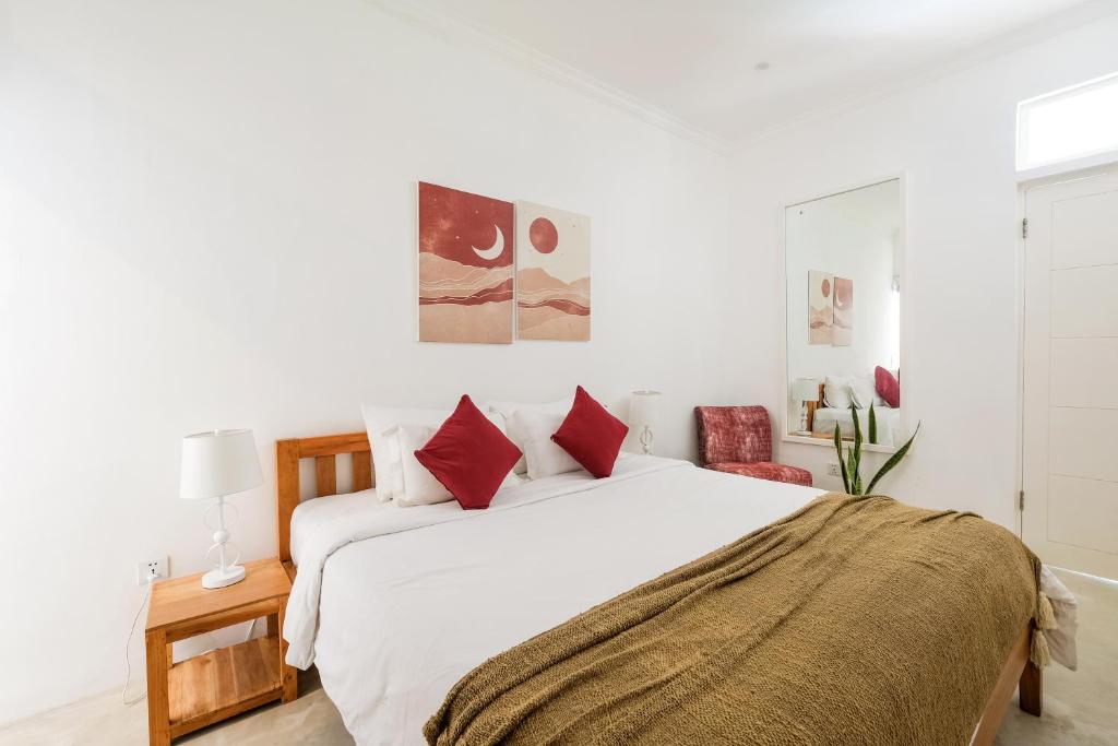 a white bedroom with a large white bed with red pillows at Villa Naia Berawa in Canggu