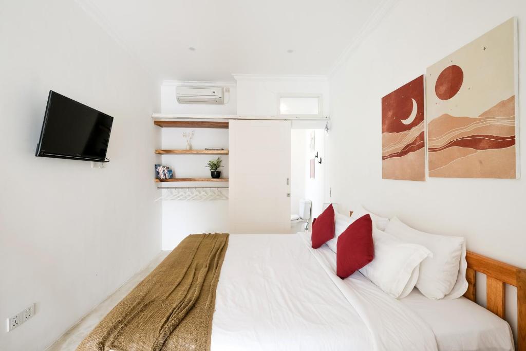 a white bedroom with a bed with red pillows at Villa Naia Berawa in Canggu