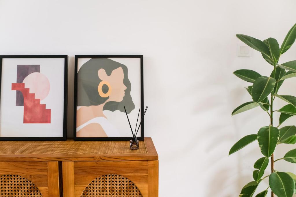 two framed art prints on a dresser next to a plant at Villa Naia Berawa in Canggu