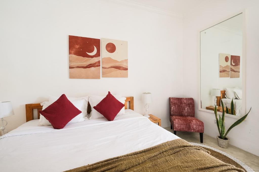 a bedroom with a white bed with red pillows at Villa Naia Berawa in Canggu