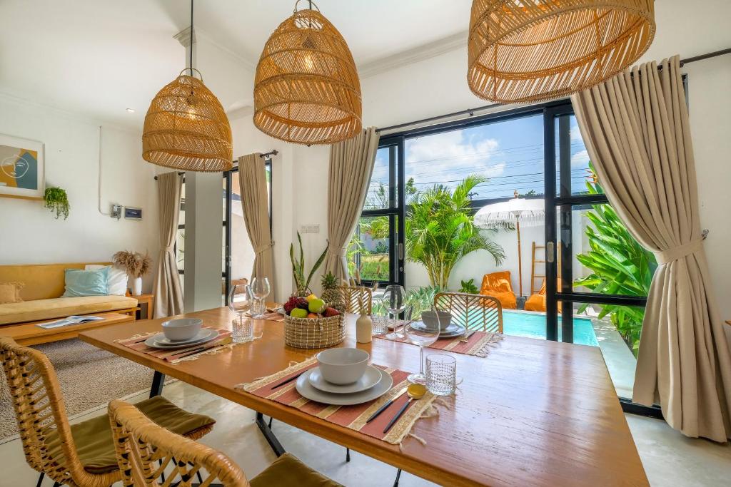 a dining room with a large wooden table and chairs at Villa Naia Berawa in Canggu