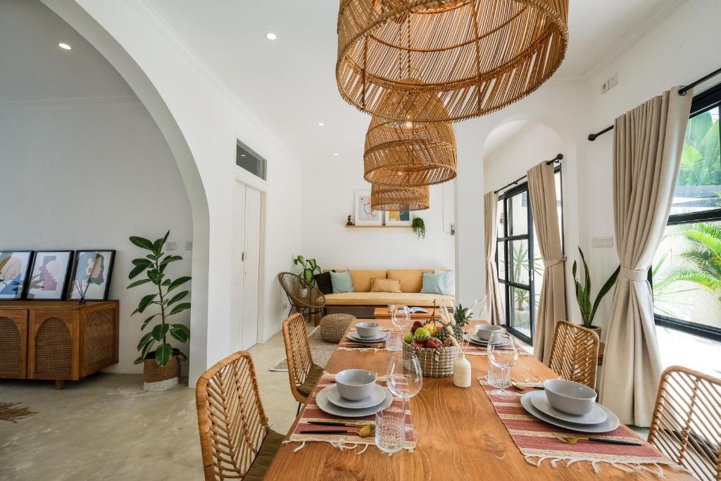 a dining room with a table and chairs and a couch at Villa Naia Berawa in Canggu